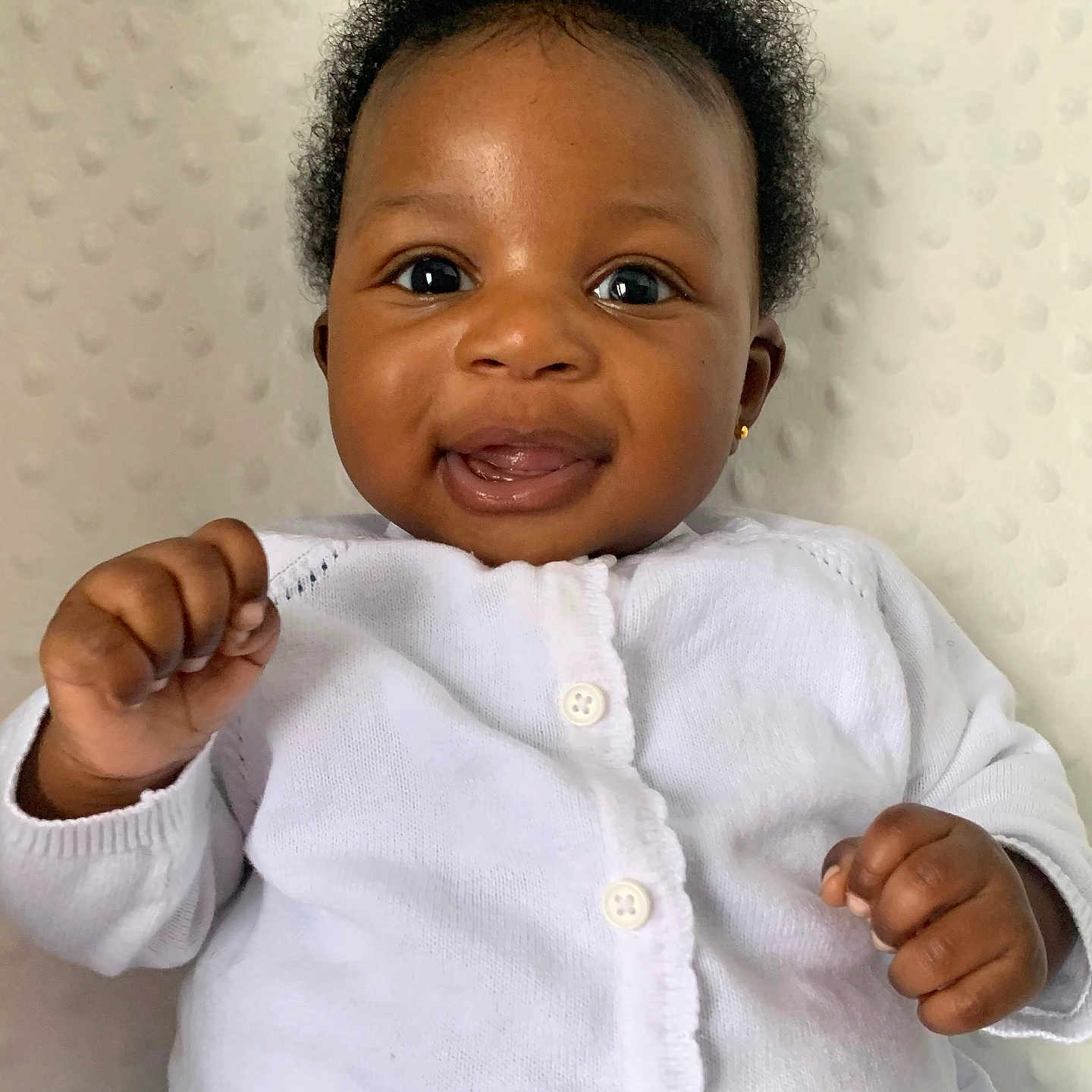 Momoririoluwa joined the competition — help win amazing prizes! baby, blue_skirt, buttoned_clothing, child, closeup, curly_hair, cute, earring, expression, face, fingers, hands, happy, indoor, infant, portrait, skin, smiling, soft_background, white_sweater