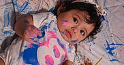 Aitana is registered to the contest to win money with this photo: toddler, child, paint, paintbrush, face_paint, colorful, art, creative, messy, canvas, headband, curly_hair, white_clothing, pink_paint, blue_paint, lying_down, expression, indoor, small_person, hands