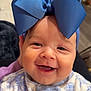 baby, smiling, blue_bow, headwear, onesie, floral_pattern, child, face, happy, cute, infant, portrait, indoor, closeup, expression, apparel, person, young_child, cheerful, adorable