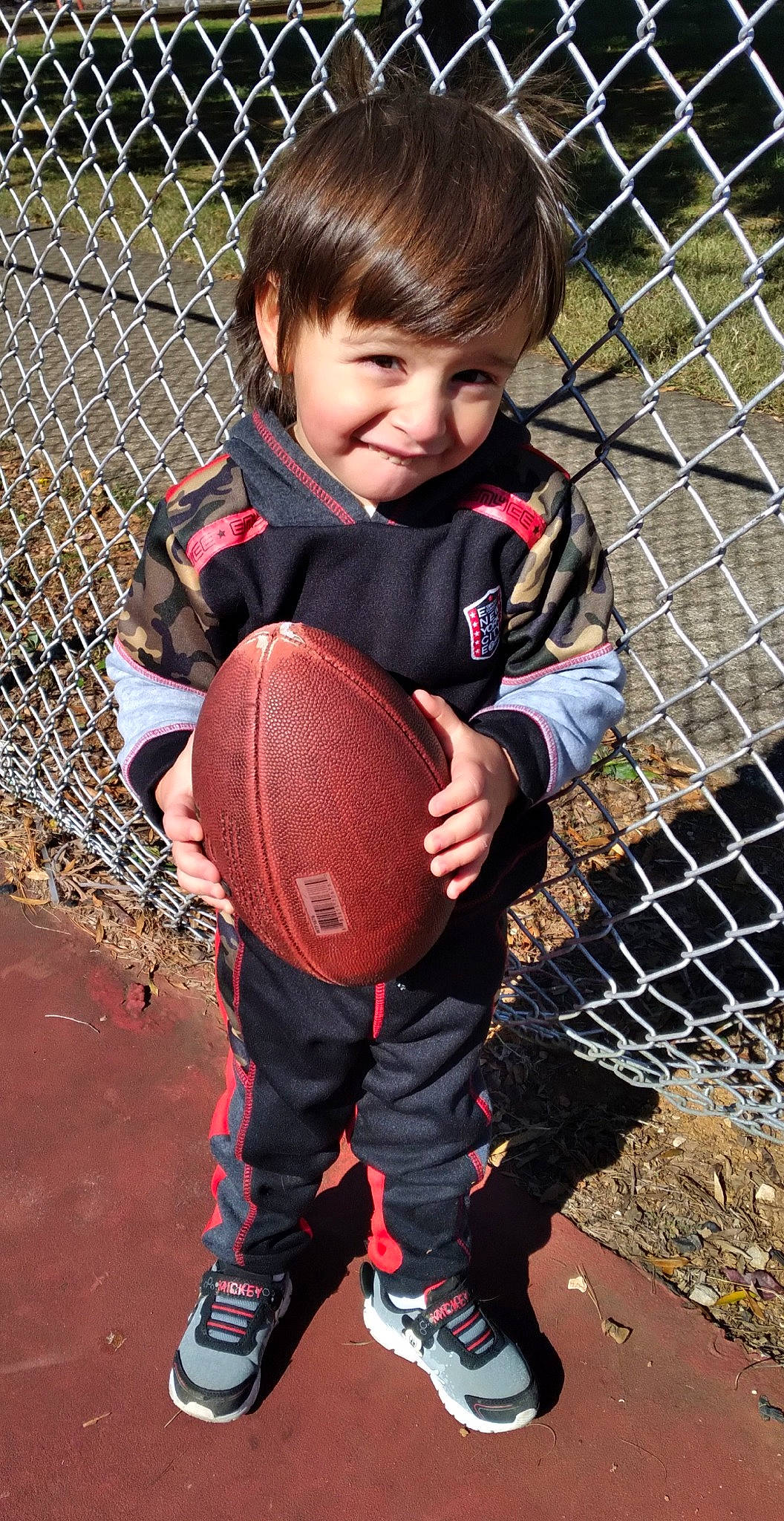 Elijah joined the competition — help win amazing prizes! ball, fence, fun, grass, happy, human_body, joy, leisure, mesh, net, people_in_nature, person, player, recreation, smile, sneakers, sports_equipment, sports_gear, thigh, toddler