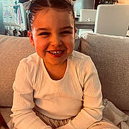 Swann a rejoint le concours — aidez-le/la à gagner de superbes lots ! child, girl, smiling, hair_buns, bow, white_shirt, sitting, couch, indoor, home, happy, portrait, furniture, plant, table, decor, cozy, cute, young, person