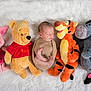 newborn, baby, sleeping, swaddled, plush_toy, stuffed_animal, winnie_the_pooh, piglet, tigger, eeyore, soft_rug, white_background, child, cute, cozy, indoors, resting, peaceful, toy_collection, infant