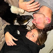 Arrow participe au concours pour gagner de l'argent avec cette photo : dog, person, smile, face, hand, black_clothing, blanket, indoor, happy, lying_down, fur, pet, playful, affection, closeup, casual, joy, friendship, human, cute