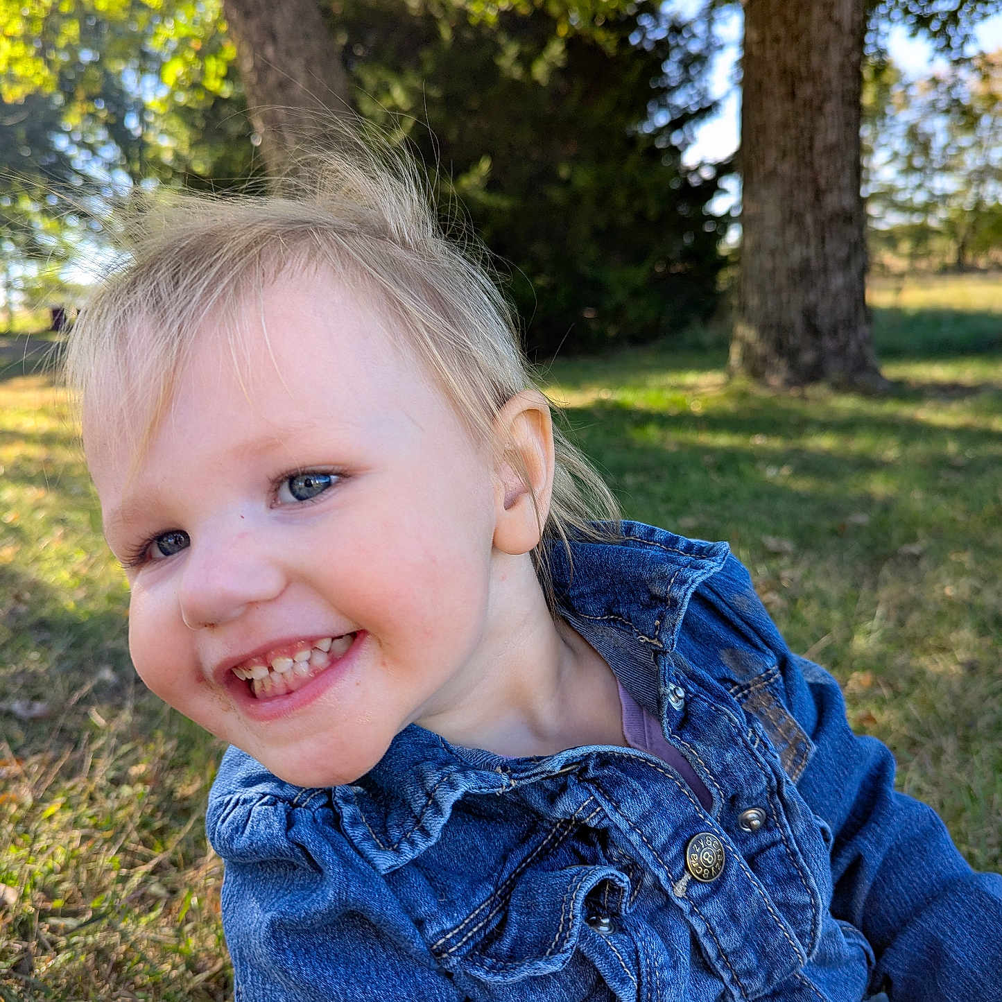 Joaleen joined the competition — help win amazing prizes! blonde_hair, blue_eyes, casual_clothing, child, cute, daylight, denim_jacket, face, grass, happy, nature, outdoor, person, playful, portrait, smiling, sunlight, toddler, tree, young_child