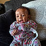 Lyric joined the competition — help win amazing prizes! baby, child, infant, smiling, happy, portrait, sitting, couch, sofa, blanket, floral_clothing, onesie, colorful, indoors, home, face, eyes, curly_hair, toy_strap, closeup