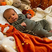 Nélio a rejoint le concours — aidez-le/la à gagner de superbes lots ! baby, infant, blanket, stuffed_animal, pumpkin, fairy_lights, orange_blanket, green_outfit, couch, cozy, soft_toys, autumn, cute, indoors, portrait, newborn, relaxing, decor, warm_lighting, child