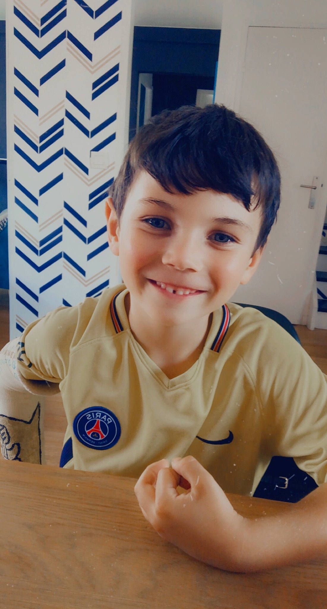 Louison participe au concours pour gagner de l'argent avec cette photo : blue, chair, child, elbow, fun, gesture, happy, job, joy, nail, person, room, shirt, shorts, sitting, sleeve, smile, t_shirt, thumb, toddler