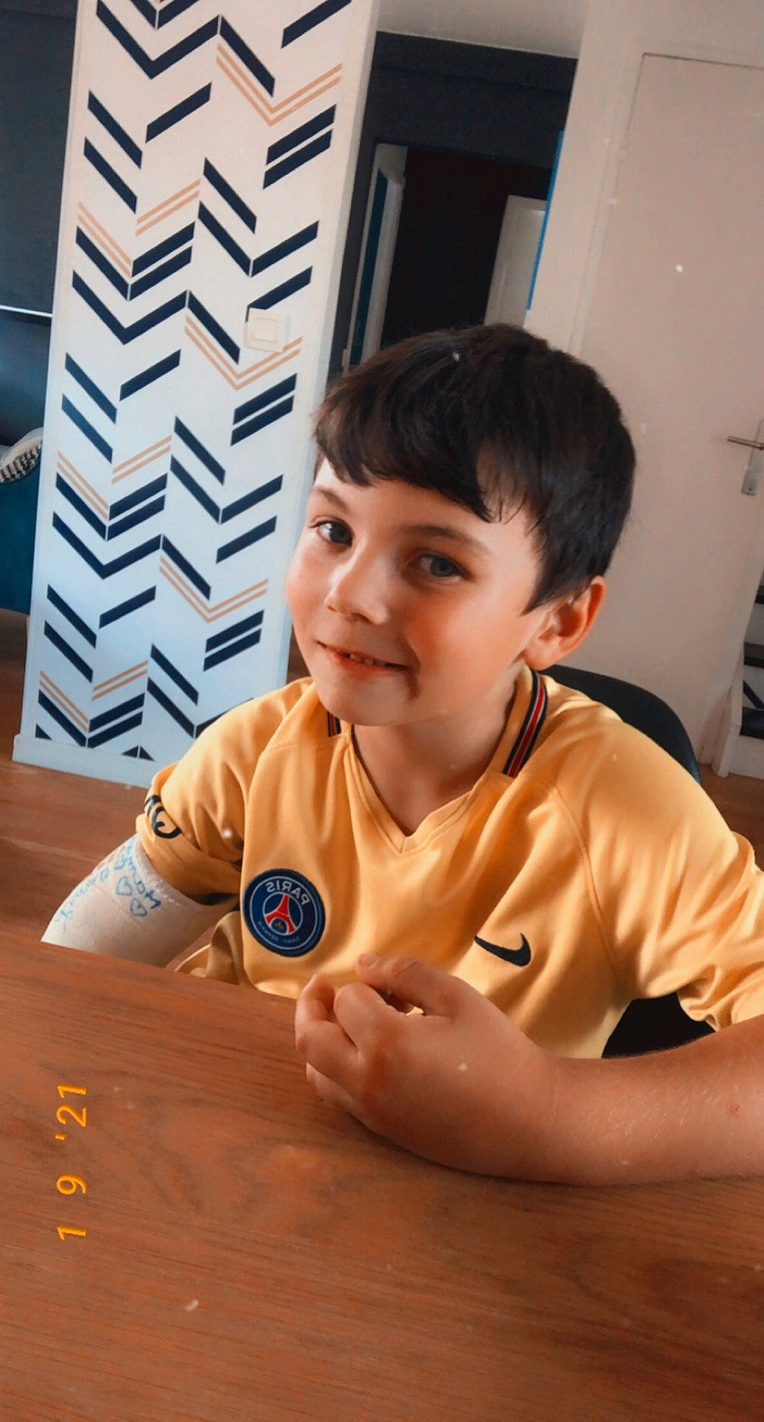 Louison participe au concours pour gagner de l'argent avec cette photo : chair, child, elbow, finger, flooring, fun, gesture, happy, hardwood, joy, mammal, person, shirt, sleeve, t_shirt, table, thumb, toddler, varnish, wood