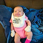 Cherish is registered to the contest to win money with this photo: baby, smiling, pink_onesie, mittens, bib, blue_blanket, couch, infant, happy, cute, indoors, polka_dot_socks, hand, face, person, child, soft_toys, cozy, relaxed, apparel