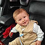 baby, child, car_seat, leather_seat, clothing, vest, bow_tie, shoe, seatbelt, car_interior, hand, smile, face, person, infant, cute, young_child, sitting, red_gloves, black_leather
