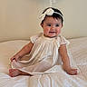 baby, bed, blanket, bow, child, cozy, cute, dress, face, happy, headband, indoors, infant, portrait, sitting, skin, smiling, soft_lighting, white, young