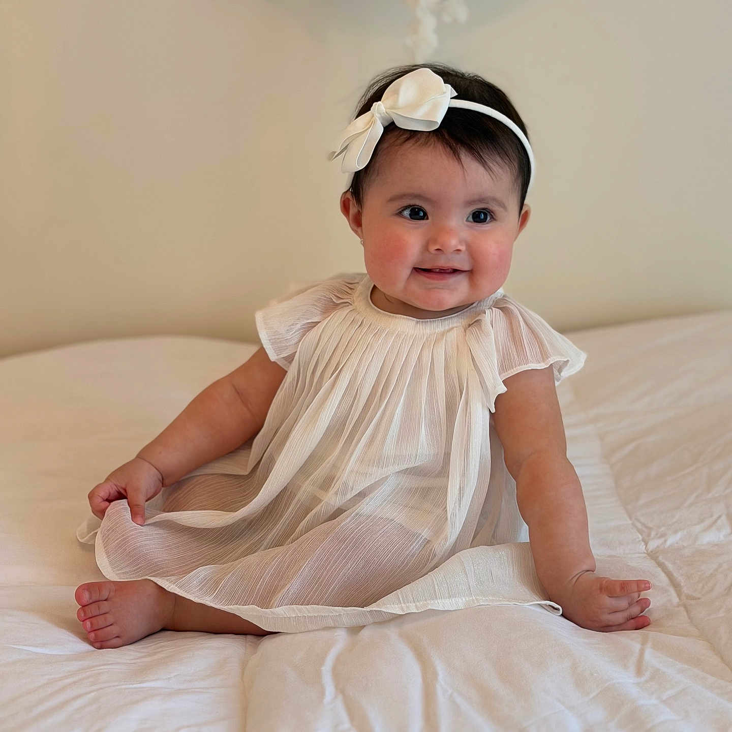 Vianka is registered to the contest to win money with this photo: baby, bed, blanket, bow, child, cozy, cute, dress, face, happy, headband, indoors, infant, portrait, sitting, skin, smiling, soft_lighting, white, young