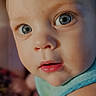 baby, child, face, blue_eyes, close_up, infant, skin, curious, portrait, app_icons, smartphone_screen, blurred_background, blue_outfit, head, expression, person, photography, indoors, human, mobile_phone
