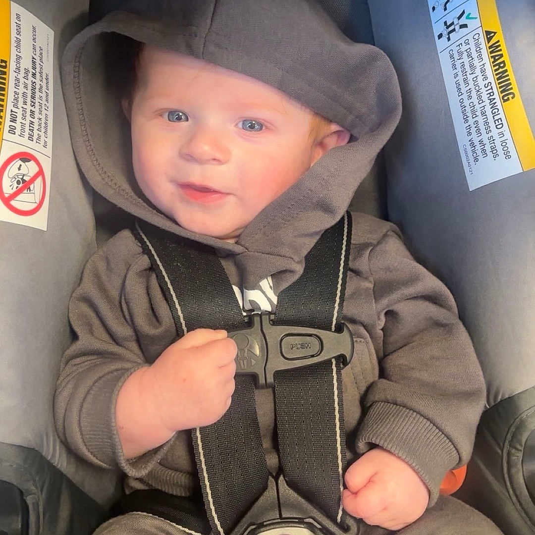 Malakai is registered to the contest to win money with this photo: adorable, baby, baby_fashion, car_seat, casual_wear, child, clothing, cute, face, hands, hoodie, indoor, infant, person, portrait, safety_harness, seatbelt, smile, young_child, young_infant