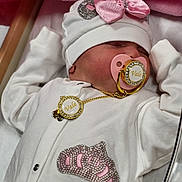 Valentina is registered to the contest to win money with this photo: baby, sleeping, pacifier, hat, pink_bow, white_outfit, rhinestones, crown_patch, gold_chain, blanket, infant, cute, peaceful, soft, clothing, child, resting, indoors, newborn, face