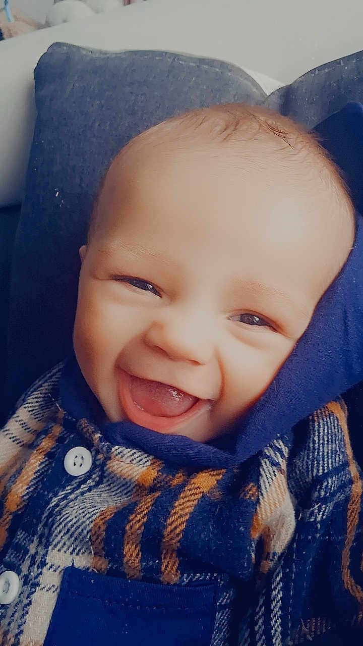 Adriano a rejoint le concours — aidez-le/la à gagner de superbes lots ! baby, smiling, face, plaid_shirt, blue, button, couch, closeup, happy, child, portrait, infant, sitting, cozy, young, cute, indoors, light, head, expression