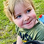child, toddler, blonde_hair, blue_eyes, smiling, outdoor, grass, toy, backpack, mesh, green_shirt, cute, portrait, happy, sitting, nature, playful, person, young_child, casual_clothing
