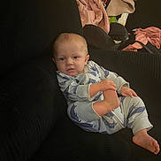 Jameson is registered to the contest to win money with this photo: baby, infant, pajamas, shark_pattern, couch, black_couch, foot, grabbing, blanket, baby_gear, indoor, child, cute, relaxed, clothing, person, furniture, portrait, cozy, home