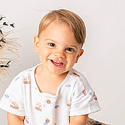 Valentin participe au concours pour gagner de l'argent avec cette photo : toddler, smiling, child, portrait, white_shirt, short_hair, indoor, neutral_background, dried_plants, vase, cute, happy, baby, face, person, light_skin, buttoned_shirt, studio_photo, young_child, casual_clothing