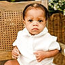 baby, child, infant, white_clothing, sitting, chair, woven_chair, portrait, indoors, cute, serious_expression, skin, hands, legs, greenery, flowers, natural_light, closeup, person, young_child
