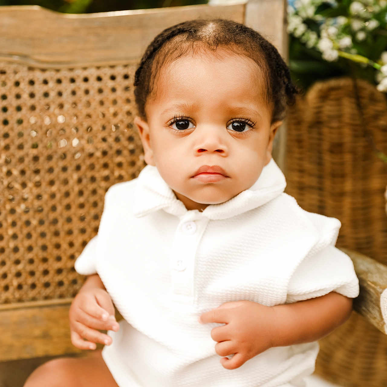 Raiden joined the competition — help win amazing prizes! baby, child, infant, white_clothing, sitting, chair, woven_chair, portrait, indoors, cute, serious_expression, skin, hands, legs, greenery, flowers, natural_light, closeup, person, young_child