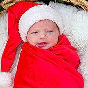 Emilia is registered to the contest to win money with this photo: baby, newborn, infant, swaddled, santa_hat, red_blanket, wicker_basket, white_fur, cozy, christmas, holiday, poinsettia, festive, portrait, closeup, cute, blue_eyes, relaxed, soft_texture, warm_colors