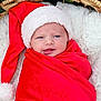 baby, newborn, infant, swaddled, santa_hat, red_blanket, wicker_basket, white_fur, cozy, christmas, holiday, poinsettia, festive, portrait, closeup, cute, blue_eyes, relaxed, soft_texture, warm_colors