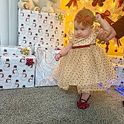 Mia is registered to the contest to win money with this photo: baby, child, dress, bow, carpet, holiday, christmas, presents, gift, teddy_bear, decorations, lights, hand, walking, indoor, celebration, cute, smiling, person, festive