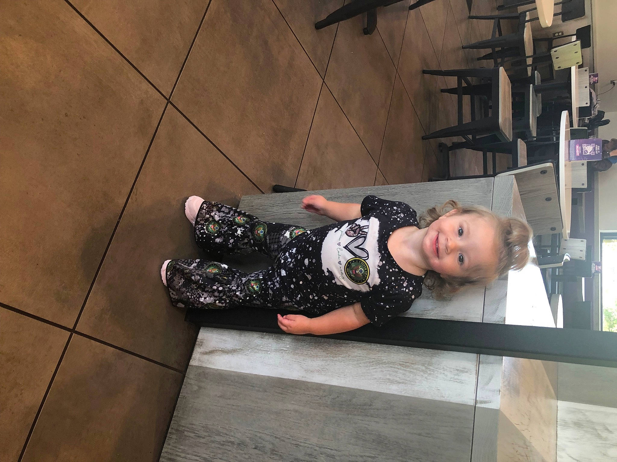 Ava joined the competition — help win amazing prizes! baby_toddler_clothing, building, child, concrete, flooring, foot, human_leg, joy, knee, pattern, person, road_surface, sidewalk, sitting, street, thigh, toddler, wood