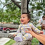 Hailey is registered to the contest to win money with this photo: baby, branch, child, clothing, daylight, face, family, greenery, hands, happy, nature, onesie, outdoor, parked_car, person, play, skin, smile, support, tree