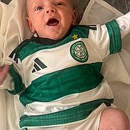 Luca joined the competition — help win amazing prizes! baby, infant, child, smiling, green, white, clothing, sportswear, football_jersey, celtic_football_club, socks, blanket, soft_surface, happy, lying_down, cute, portrait, indoor, face, person