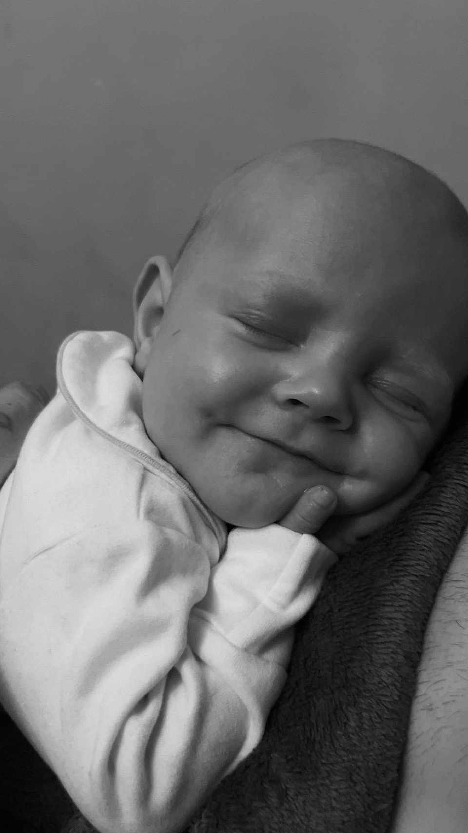 Luca is registered to the contest to win money with this photo: baby, sleeping, smile, face, infant, closed_eyes, cute, peaceful, soft_clothing, blanket, portrait, newborn, resting, child, cozy, skin, head, hand, indoors, monochrome
