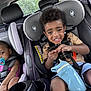 child, toddler, car_seat, sippy_cup, pacifier, smiling, seat_belt, car_interior, window, greenery, shorts, tshirt, hair, earrings, safety, baby, cute, two_children, car_trip, happy