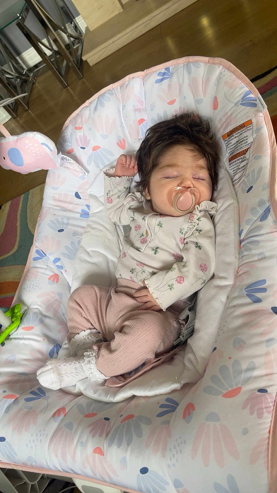 Alaina is registered to the contest to win money with this photo: baby, infant, sleeping, pacifier, baby_seat, floral_pattern, pink_clothing, white_socks, wooden_floor, carpet, indoor, child, cute, resting, cozy, soft_toys, home, peaceful, person, newborn