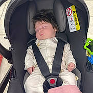 Alaina joined the competition — help win amazing prizes! baby, car_seat, sleeping, infant, pajamas, pink_socks, blanket, floor_tiles, black_car_seat, child, indoor, baby_clothing, safety_harness, head_support, footwear, person, resting, cute, soft_toy, toddler