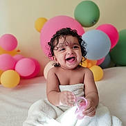 Jeshna joined the competition — help win amazing prizes! baby, child, smiling, laughing, towel, curly_hair, toy, pink_toy, balloons, colorful, indoor, portrait, happy, cute, infant, celebration, soft_texture, playful, fun, joyful