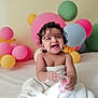 baby, child, smiling, laughing, towel, curly_hair, toy, pink_toy, balloons, colorful, indoor, portrait, happy, cute, infant, celebration, soft_texture, playful, fun, joyful