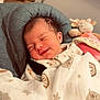 baby, newborn, smile, blanket, stars, planets, plush_toy, cushion, sleeping, infant, cozy, indoor, cute, child, soft, resting, face, clothing, peaceful, portrait