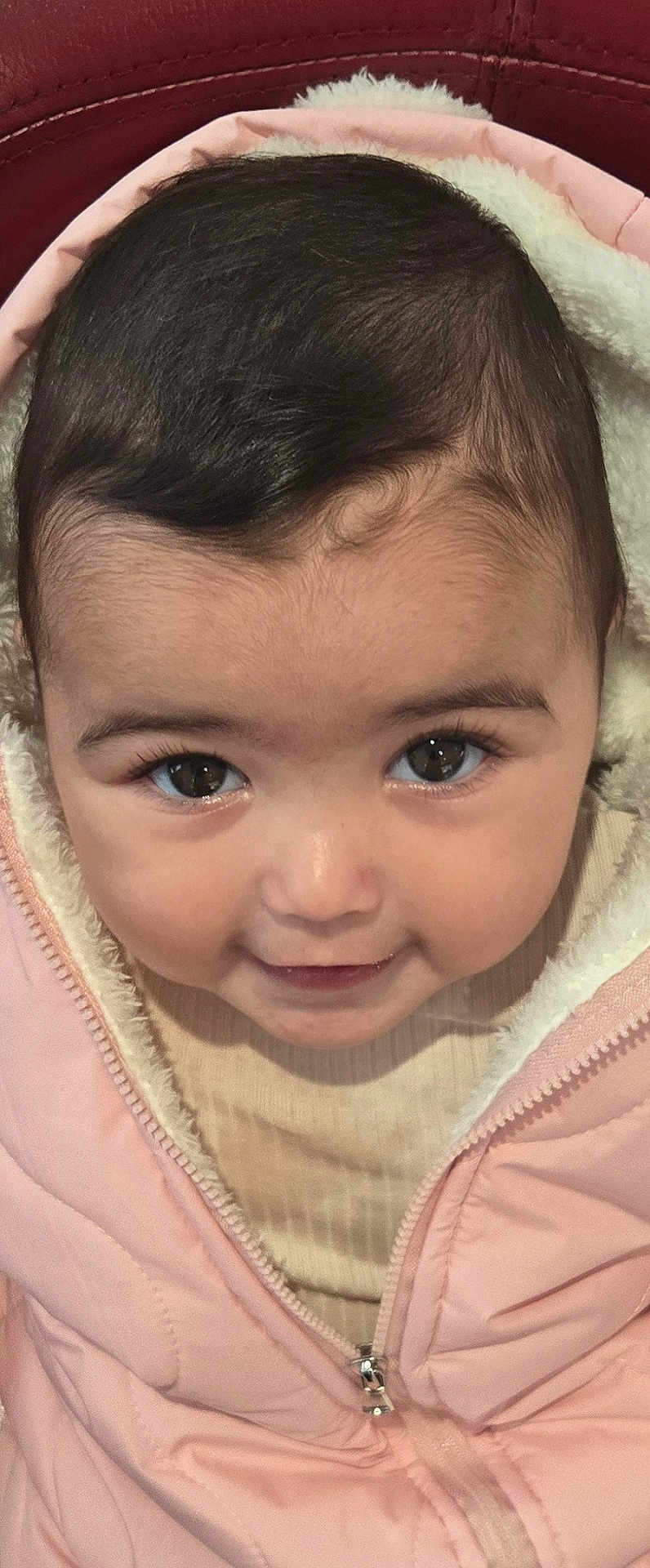 Lea participe au concours pour gagner de l'argent avec cette photo : baby, child, face, eyes, smile, pink_jacket, fuzzy_lining, close_up, infant, portrait, warm_clothing, cute, young_child, looking_up, skin, hair, zipper, apparel, indoors, warmth