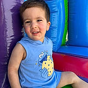Elias is registered to the contest to win money with this photo: toddler, child, smiling, blue_outfit, cookie_monster, inflatable, play_structure, colorful, purple, blue, green, red, sitting, happy, face, short_hair, indoor, casual_clothing, cute, playful