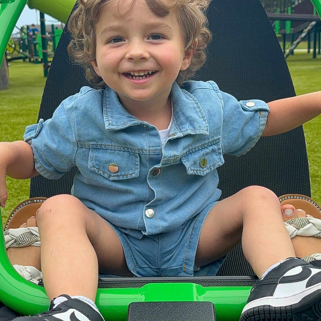 Timmy is registered to the contest to win money with this photo: baby, clothing, face, footwear, grass, head, nature, outdoorplayarea, outdoors, pants, park, person, photography, plant, playarea, portrait, shoe, shorts, sneaker, summer
