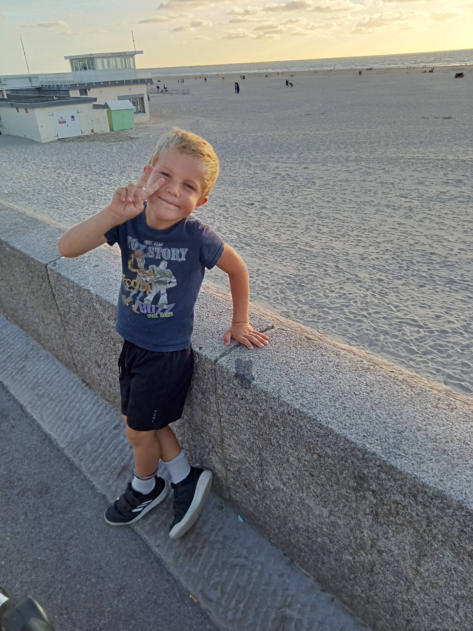 Kylian a rejoint le concours — aidez-le/la à gagner de superbes lots ! asphalt, child, fun, happy, horizon, human_leg, joy, knee, leisure, ocean, pedestrian, person, recreation, shorts, sky, smile, standing, t_shirt, toddler, travel