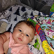 River joined the competition — help win amazing prizes! baby, infant, pink_bib, blanket, bottle, toy, colorful, face, skin, blue_eyes, lying_down, indoor, closeup, cute, child, young, soft, expression, person, playpen
