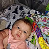 baby, infant, pink_bib, blanket, bottle, toy, colorful, face, skin, blue_eyes, lying_down, indoor, closeup, cute, child, young, soft, expression, person, playpen