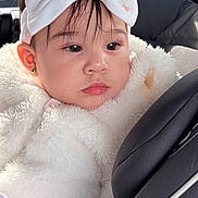 Elif is registered to the contest to win money with this photo: baby, child, car_seat, headband, bow, fluffy_clothing, earrings, face, portrait, indoor, seatbelt, car, cute, young_child, soft_light, pink, white, clothing, infant, expression