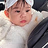 baby, child, car_seat, headband, bow, fluffy_clothing, earrings, face, portrait, indoor, seatbelt, car, cute, young_child, soft_light, pink, white, clothing, infant, expression