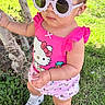 Elif joined the competition — help win amazing prizes! toddler, child, grass, tree, sunglasses, pink_clothing, hello_kitty, hair_clip, outdoor, sunny, shoes, cute, fashionable, baby, person, greenery, summer, playful, portrait, casual