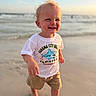 Kashton is registered to the contest to win money with this photo: toddler, child, beach, sand, ocean, waves, sunset, curly_hair, smiling, barefoot, tshirt, shorts, outdoor, happy, walking, sunlight, nature, sky, water, portrait