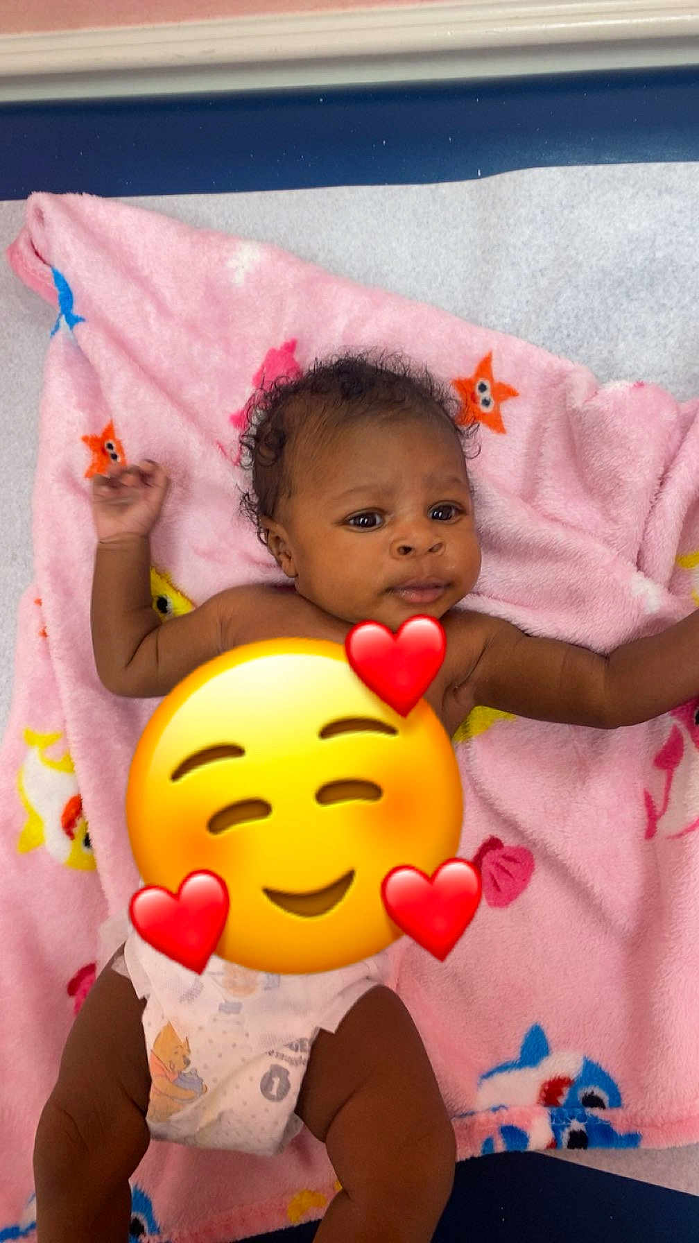 Keziah is registered to the contest to win money with this photo: baby, infant, diaper, pink_blanket, stars, fish, curly_hair, lying_down, indoor, cute, child, smiling_emoji, hearts, soft_texture, playful, skin, expression, colorful, comfort, young_child