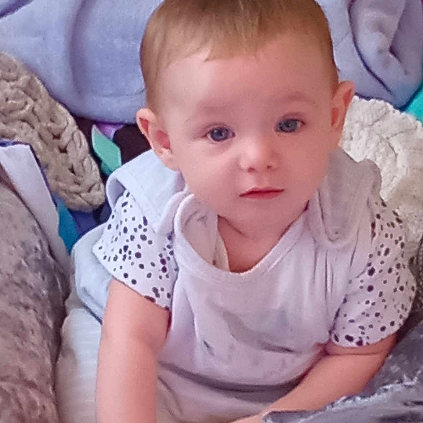 Tory is registered to the contest to win money with this photo: baby, blanket, blue_eyes, casual, child, clothing, colorful, comfort, cute, face, home, indoor, infant, person, playtime, portrait, sitting, soft_toys, toys, young_child